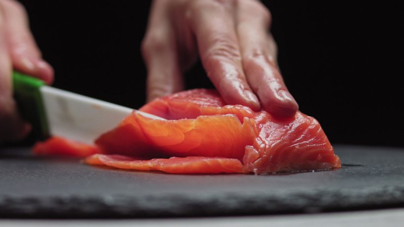 A close-up view of a cutting thin slices of fresh raw fish.