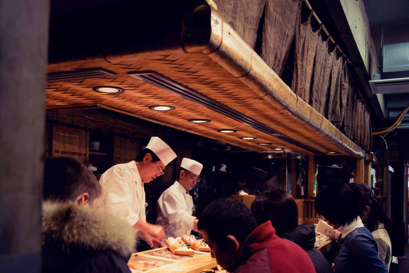 Street vendor stall selling sushi to hungry customers.