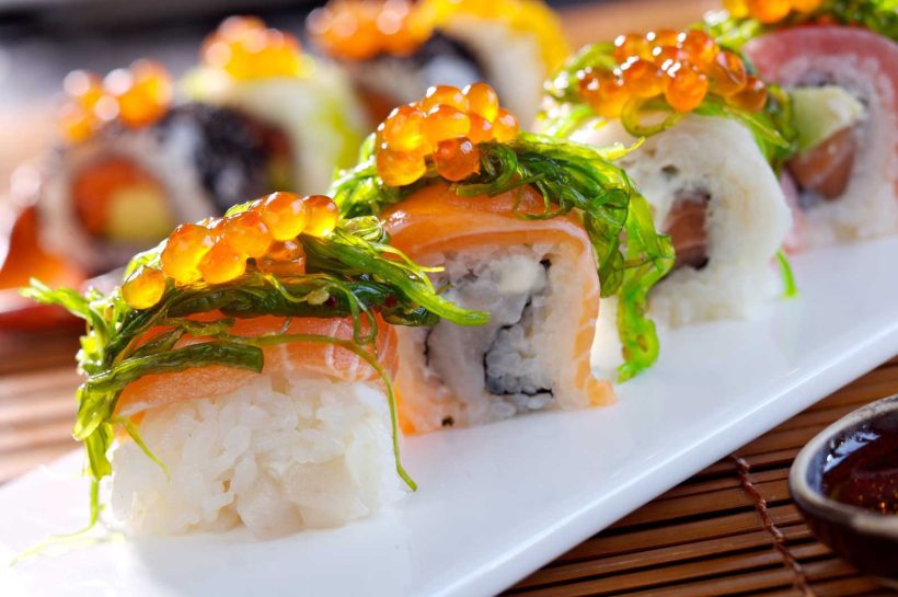A close-up shot of a sushi roll with seaweed and roe.
